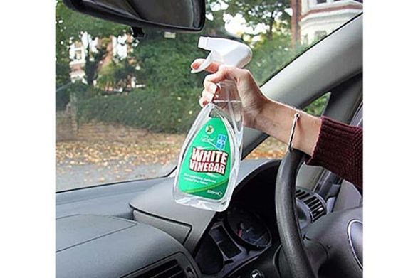 a bottle of white vinegar being sprayed onto a car windshield to clean it