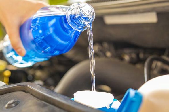 windshield wiper fluid being poured into the reservoir of a car