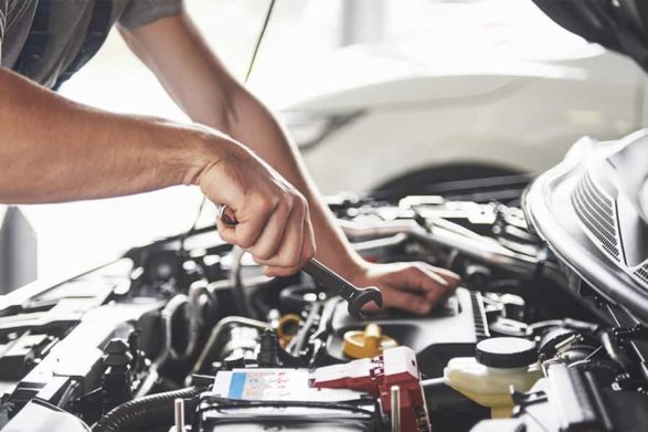 a mechanic does work on an engine under a car hood