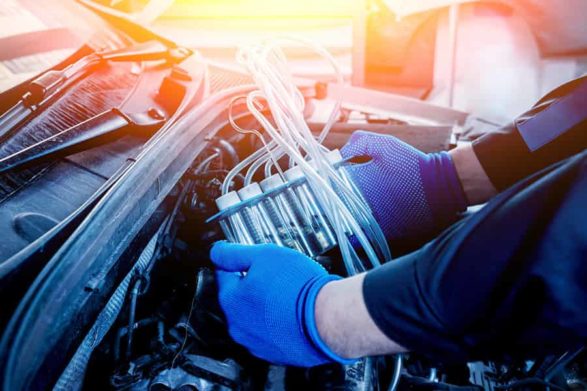 a mechanic holding fuel injectors under a car hood